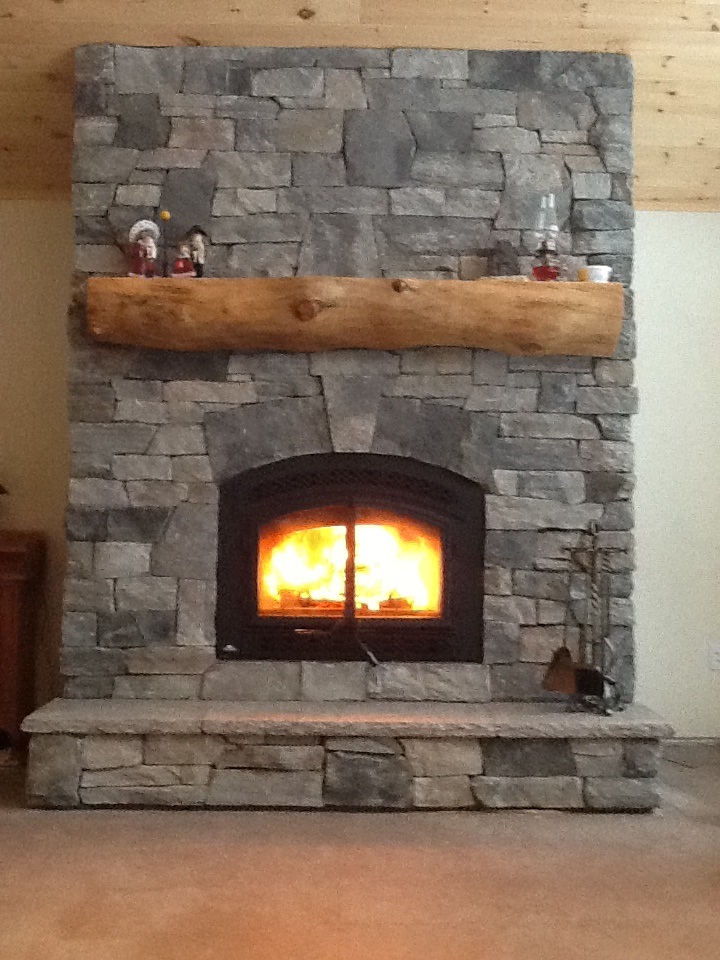 Larger image of granite stone veneer fireplace with fire on