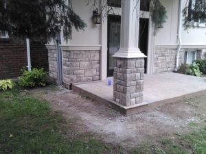 A front entrance that has been enhanced with the addition of cultured stone pillars