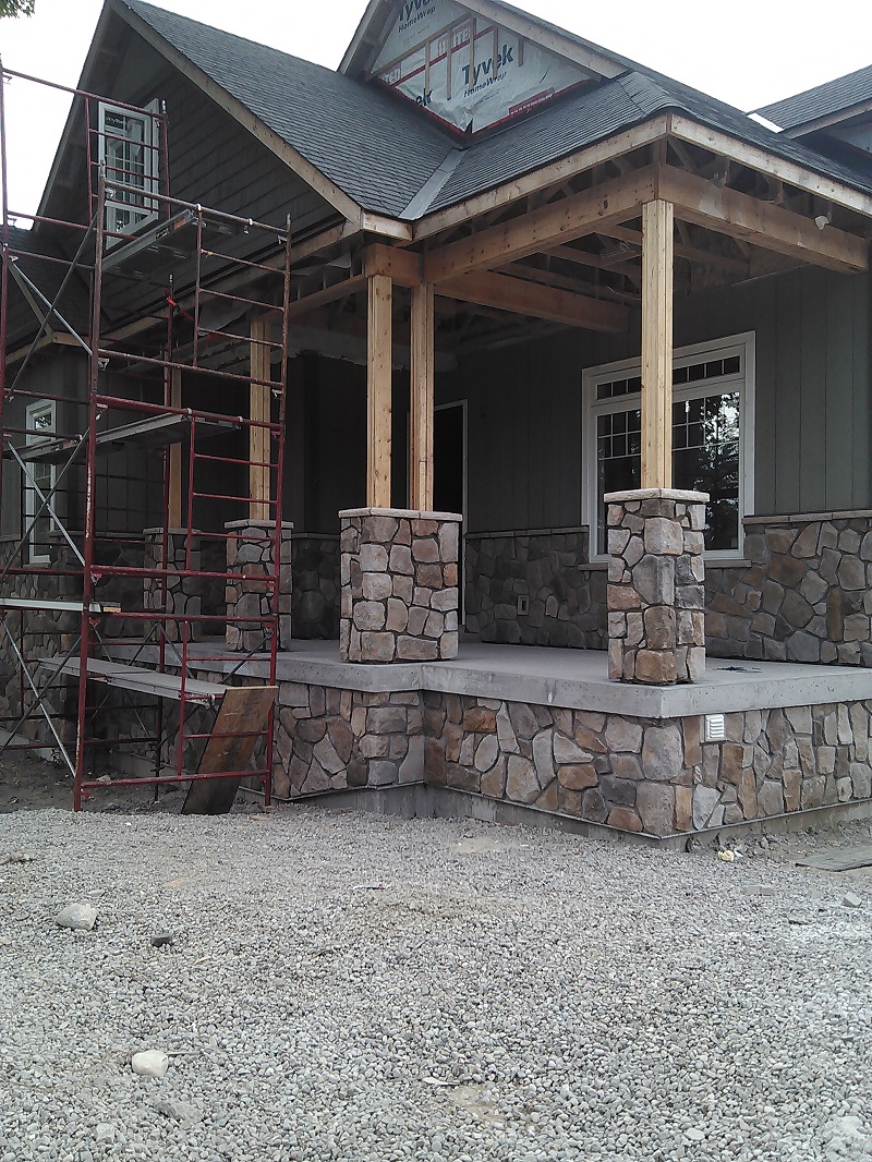 A Craftsman style home with cultured stone pillars on the front porch.