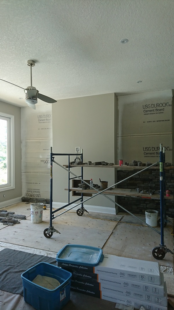 Stone veneer being applied to an accent wall. Stone veneer applied to a living room wall.
