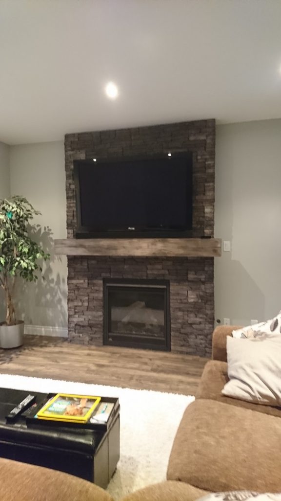 TV mounted on a stone veneer fireplace in a living room.