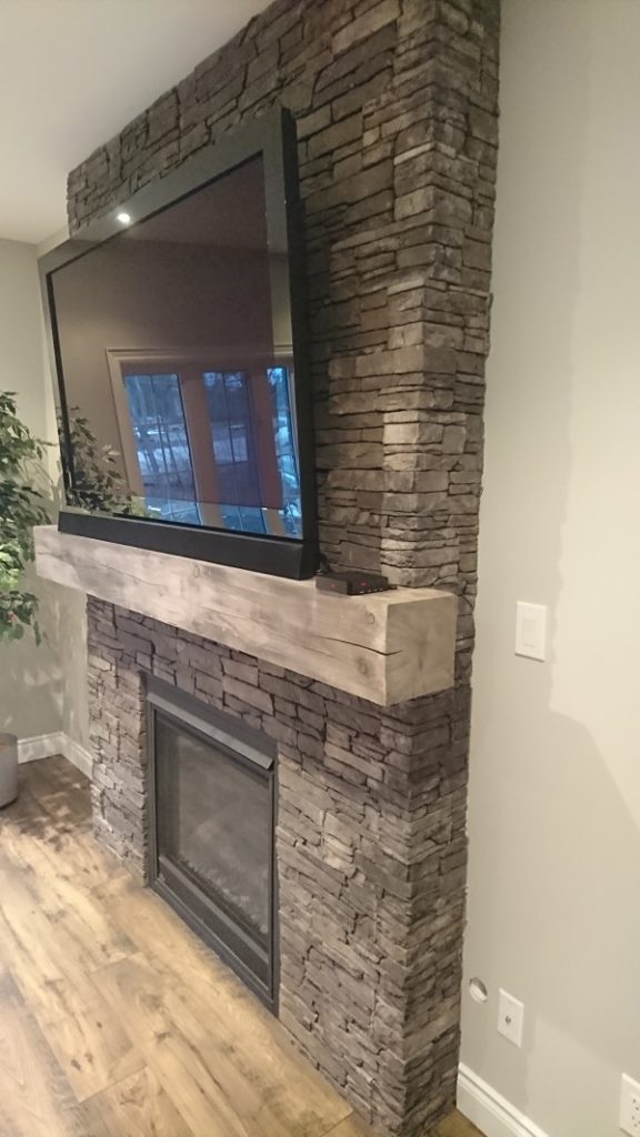 Side view of farmledge Westchester stone veneer by Stonecraft on a fireplace.