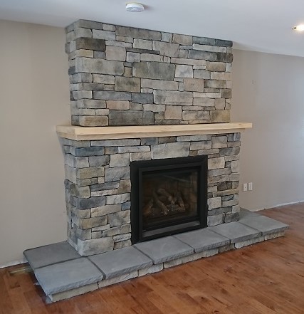 Fireplace mantle done as a two tiered shelf with upper portion of stone set back